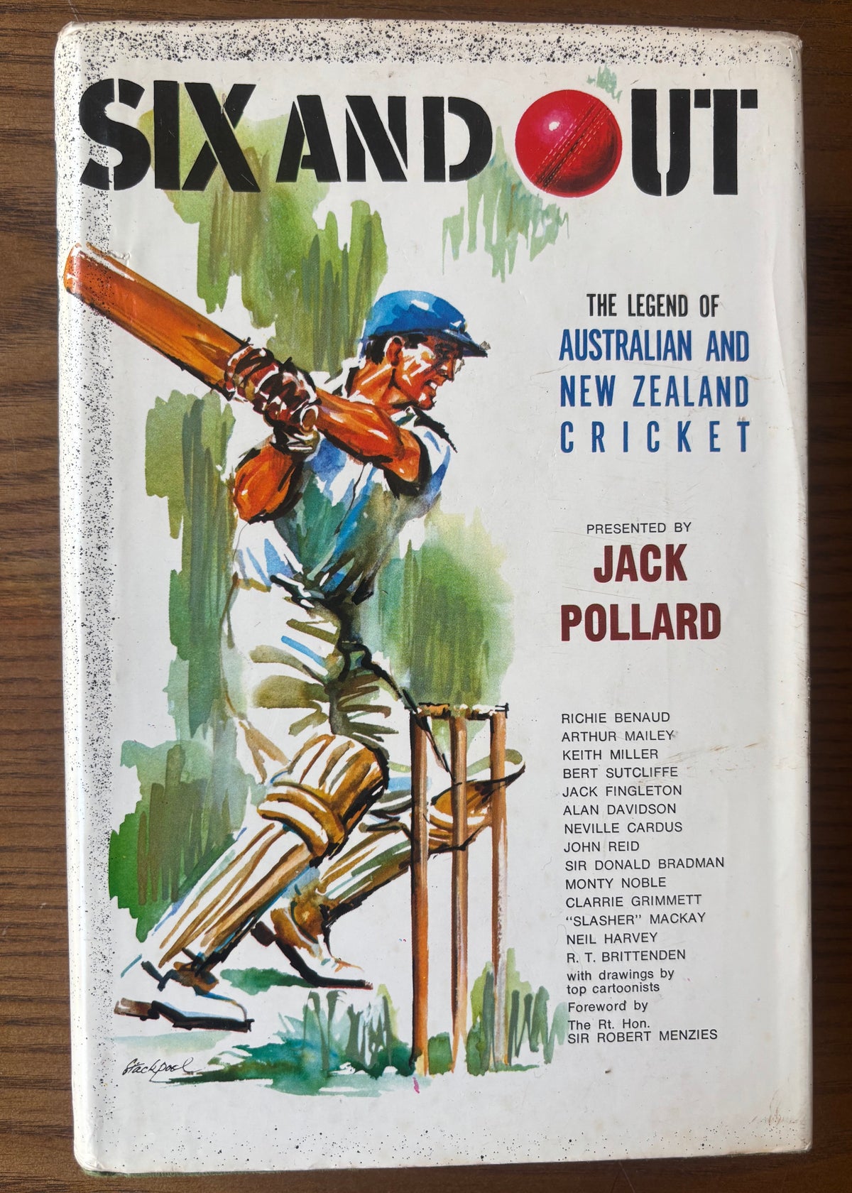 Vintage book titled 'Six and Out: The Legend of Australian and New Zealand Cricket' by Jack Pollard, featuring an illustrated cricket player on the cover, photographed on a wooden surface.